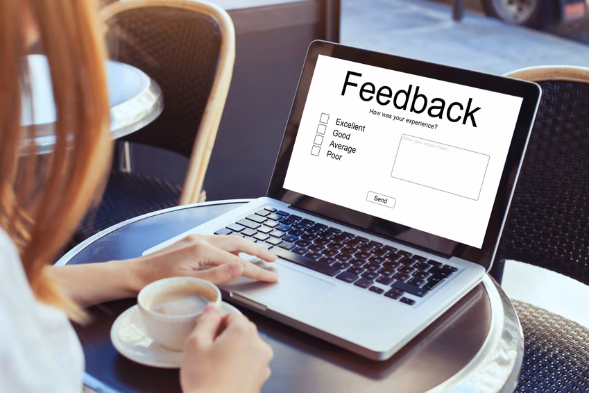 Woman's hands with coffee cup, typing review feedback on laptop